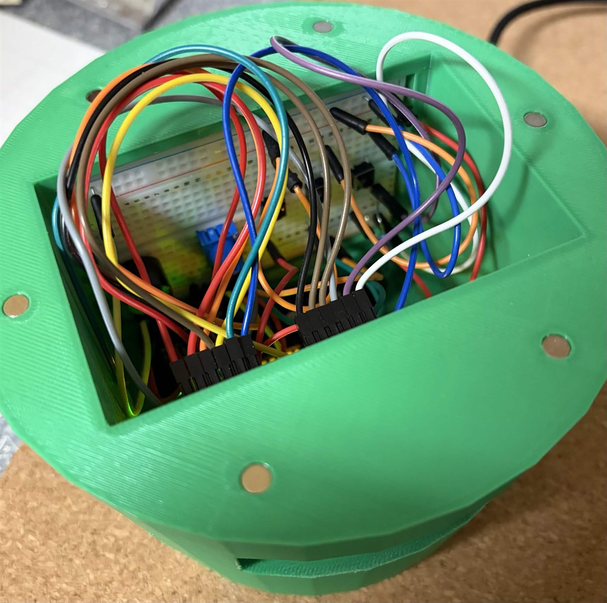 Inside the green 3D-printed desk robot with an Arduino and jumper wires